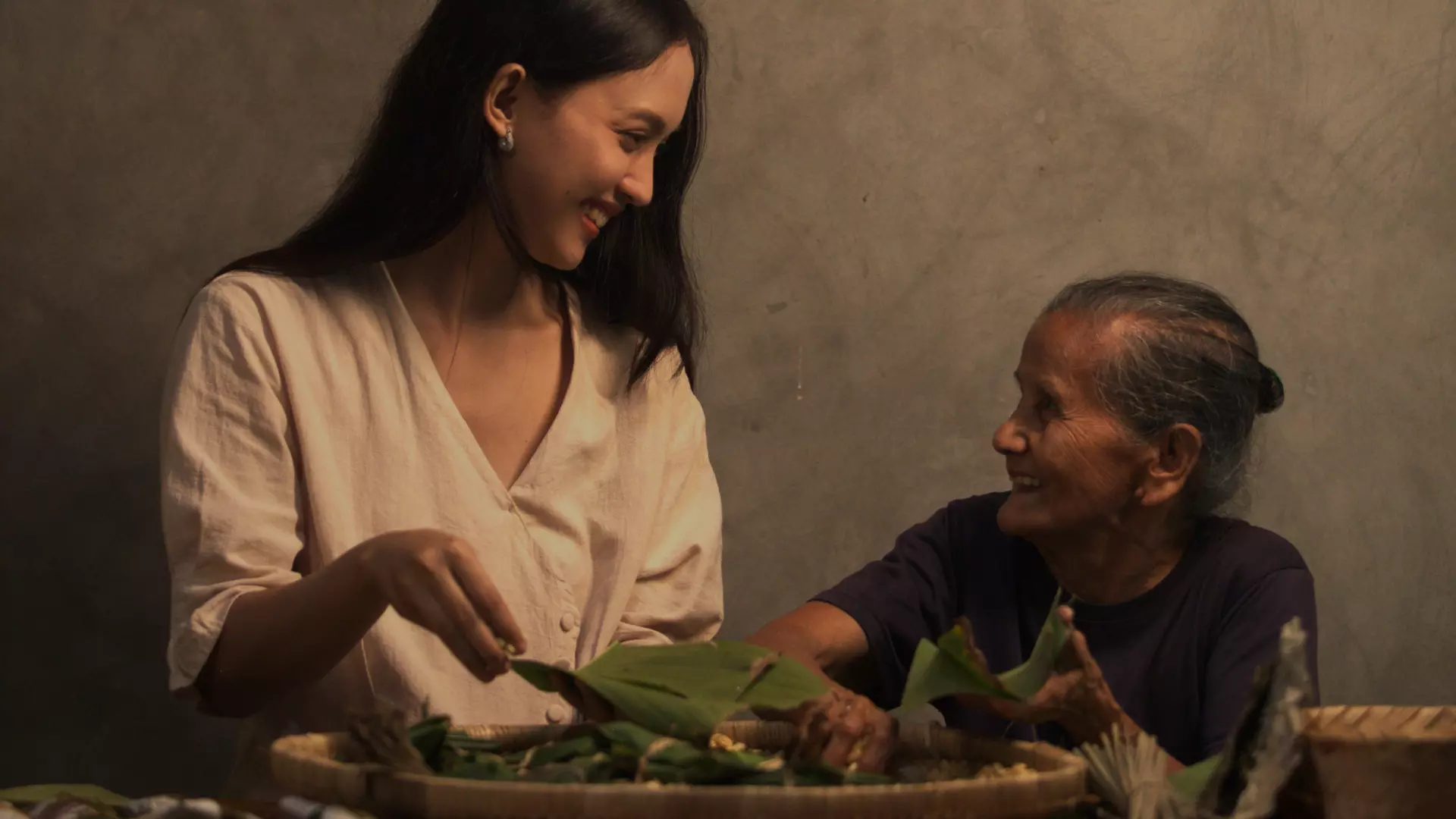 A woman and humble old woman are chatting while making tempe