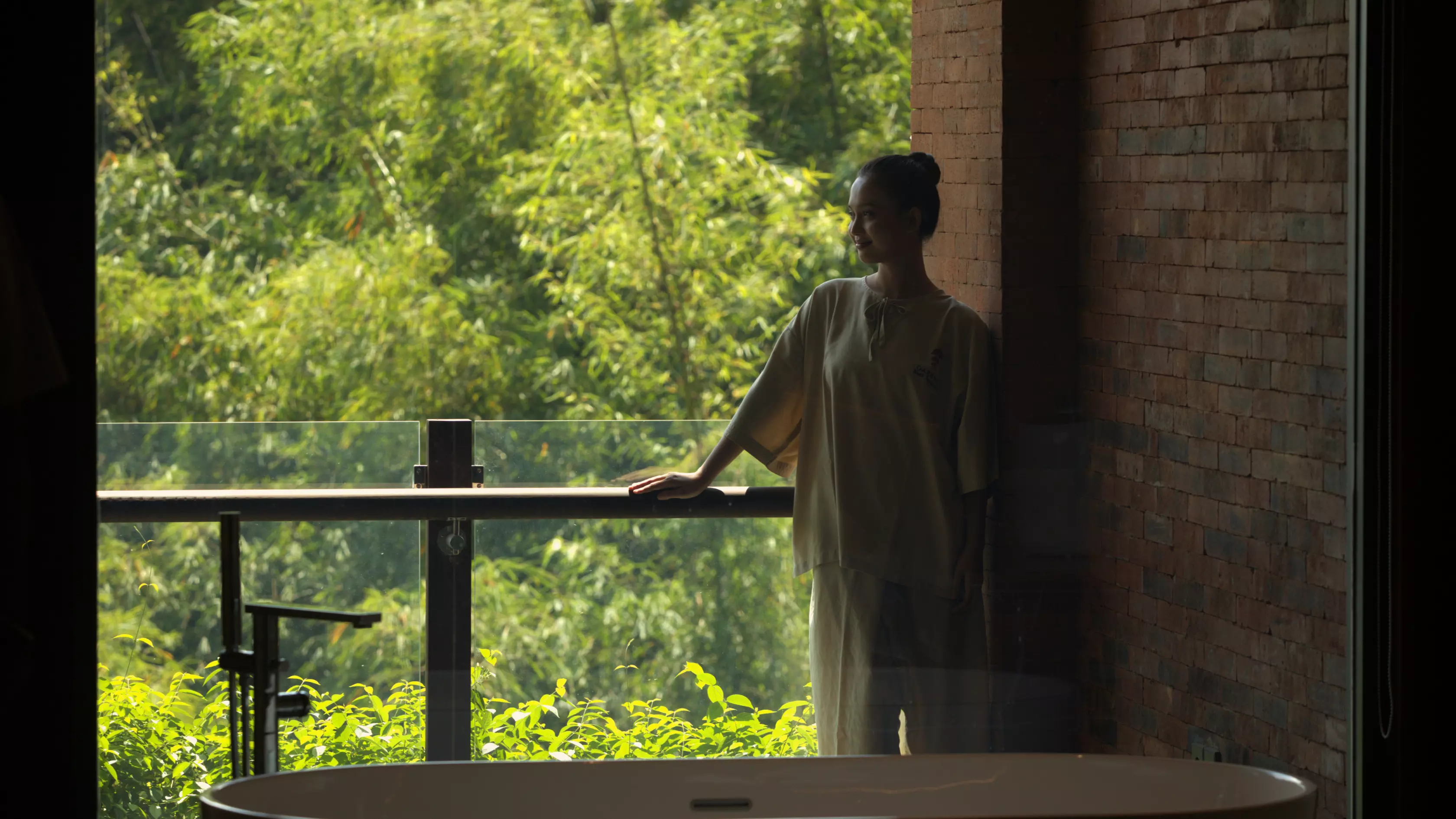 A woman is standing in spa room balcony immersing with the nature