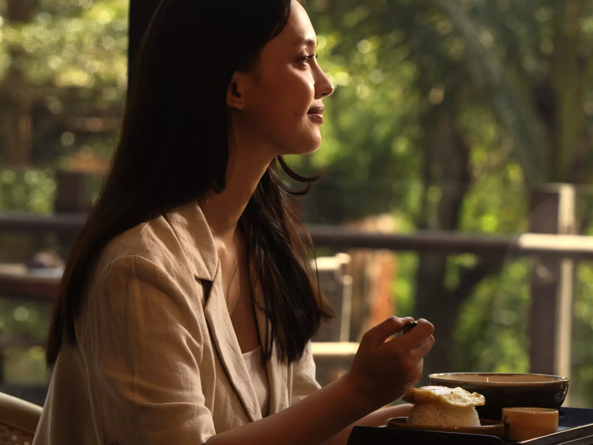 A woman is eating at the restaurant amidst the serene nature