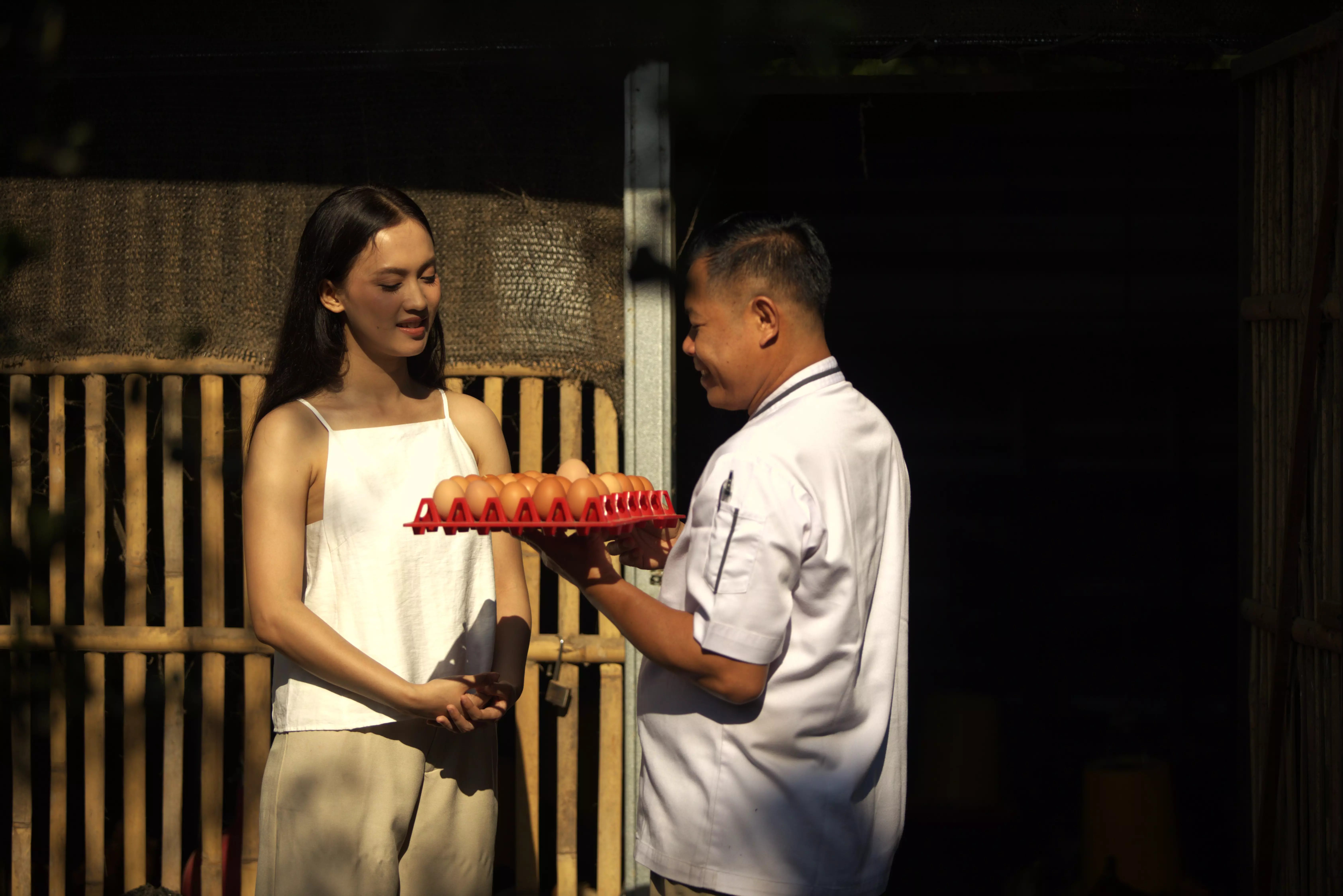 A woman and a chef are conversing in front of chicken hut.