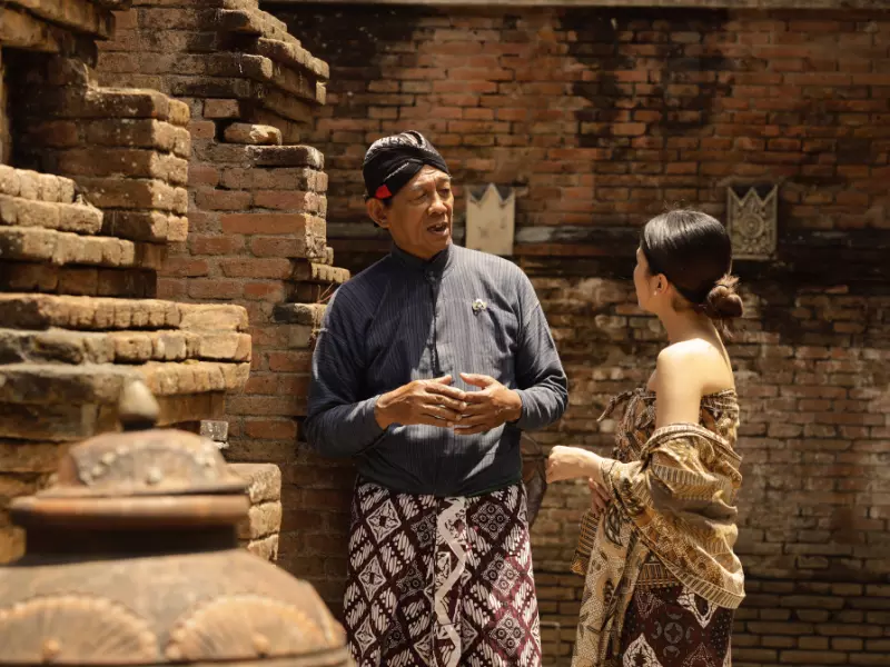 a javanese tour guide explains the history of Kotagede to a woman