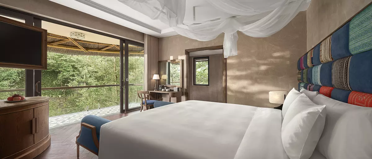 Spacious bedroom with canopy bed faces large window, offering lush forest views at Garrya Mù Cang Chải.