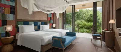 Wellbeing Suite Twin bedroom overlooking forested mountain greenery.