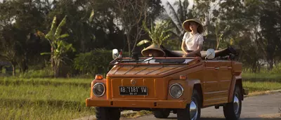 A woman on a classic car tour amidst the rice field in Sleman village