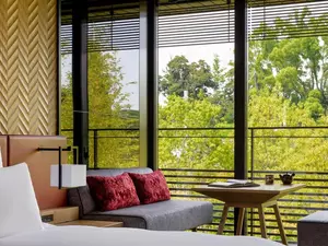 Sofa facing lush greenery through Garrya Nijo Castle View King's large window, beside a small table.