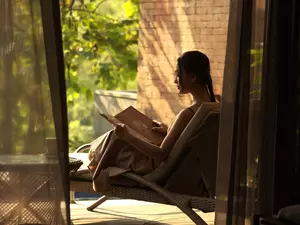 A woman is sitting on chair and reading a book