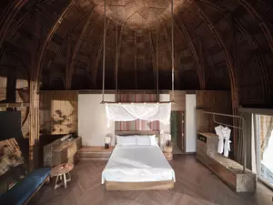 Mù Cang Chải Pool Suite bedroom with high ceiling and bamboo-inspired architecture.